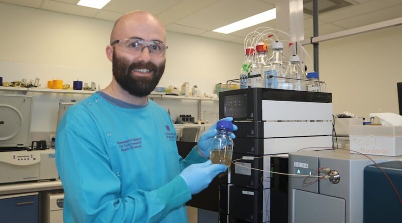 Picture of Dr. Rory Verhagen holding a wastewater test tube wearing hoofs