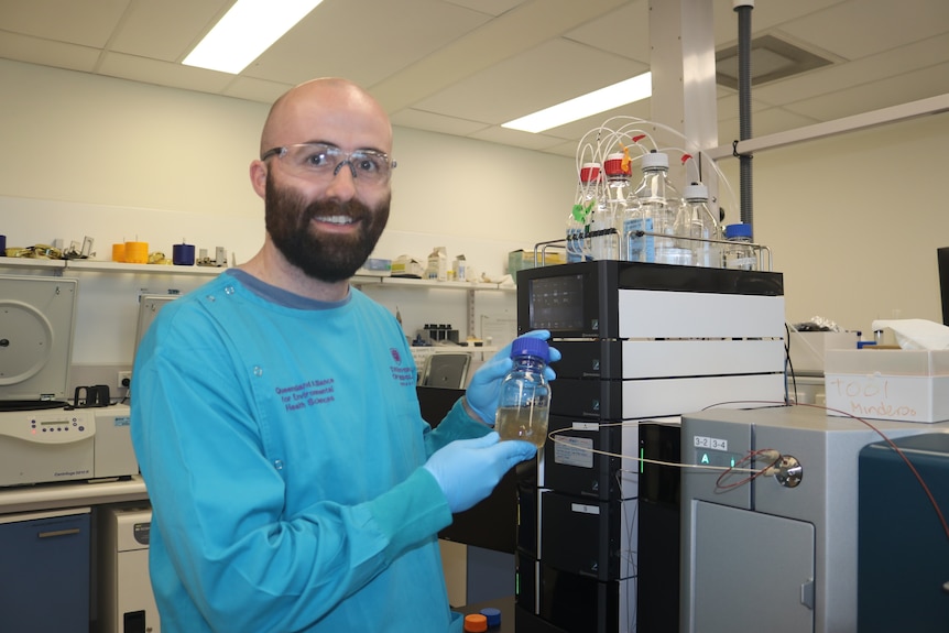 Picture of Dr. Rory Verhagen holding a wastewater test tube wearing hoofs